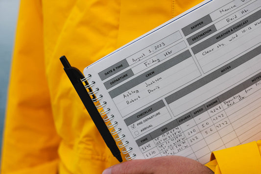 Photo: Marine cruising logbook with a pen in the hands