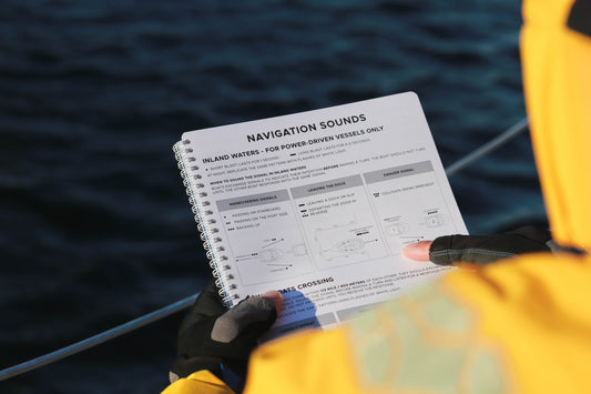Photo: Sailor Holding a Cruising Logbook with Navigational Sounds Page open