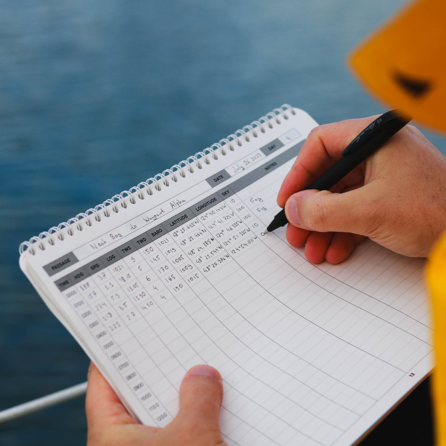 Photo: Sailor writing in a sailing logbook with all-weather pen